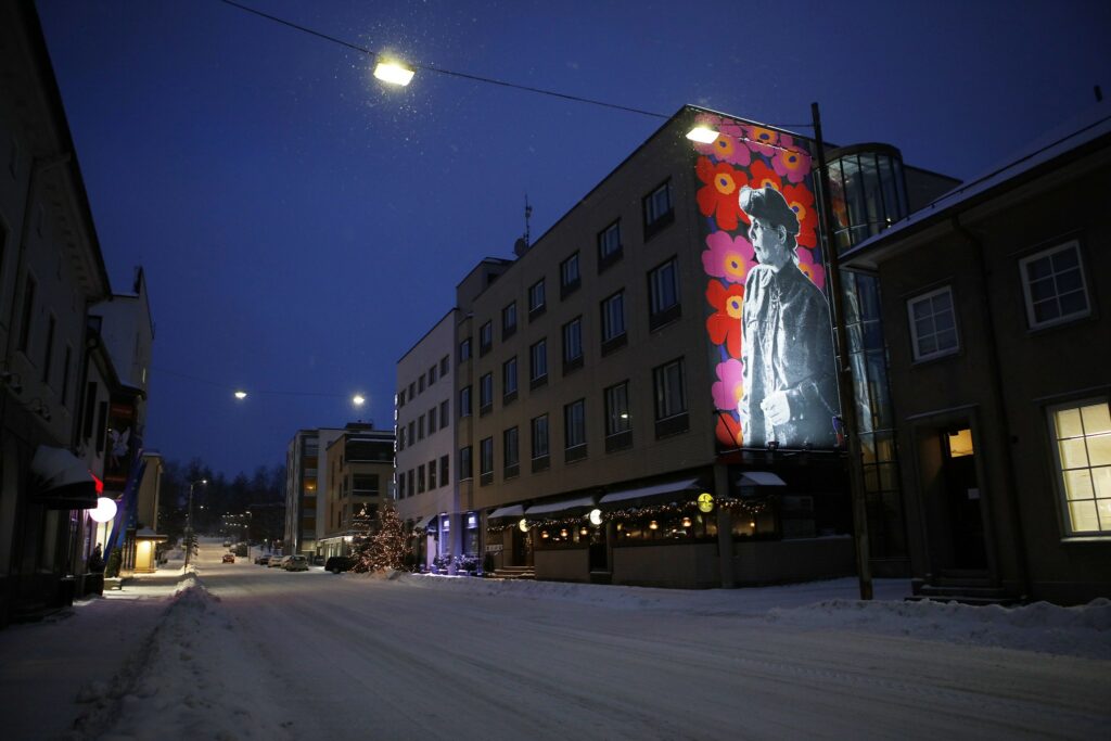 Riihimäen keskustan Maija Isolasta tehty seinämuraali hämärässä iltavalaistuksessa