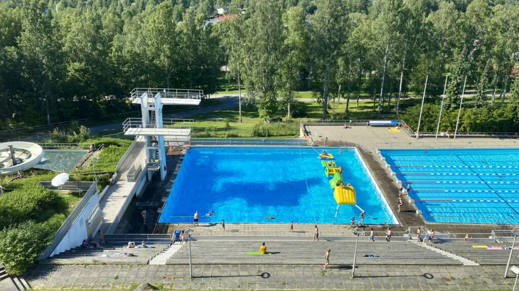 Maauimala altaineen ja hyppytorneineen. Taustalla puita.