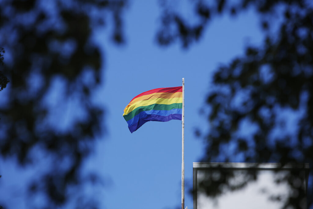 Pride-lippu liehuu sinistä taivasta vasten.
