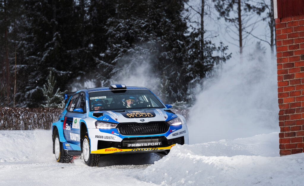 Ralliauto talvisessa maisemassa.