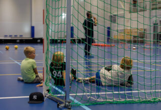 pikkupoikia pelaamassa salibandya urheiluhallissa