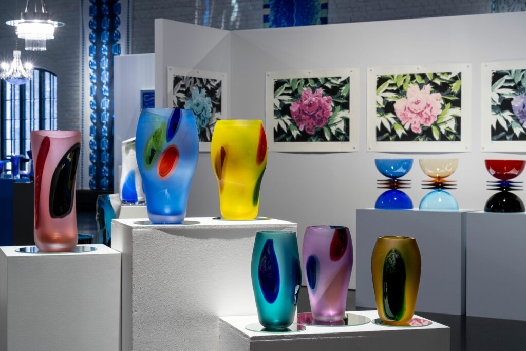 suomen lasimuseo Markku Pirin näyttelystä kuva, jossa värikkäitä lasiesineitä.