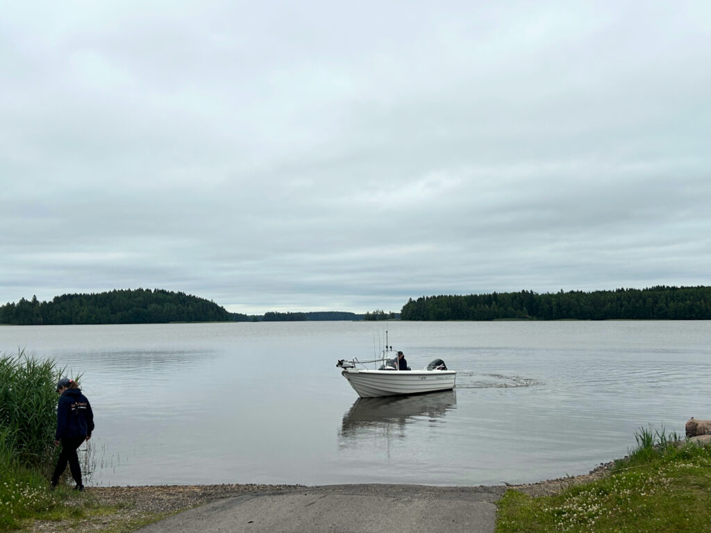 Pieni moottorivene saapumassa järvenrannan betoniselle luiskalle.